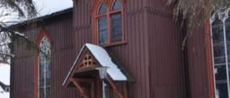 En trækirke med et stejlt tag og et kors på toppen.
