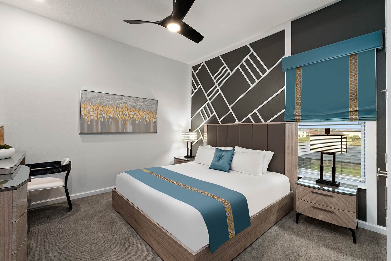 A modern hotel room with a large bed, a desk, a chair, a ceiling fan, a window with blinds, and a wall-mounted lamp.