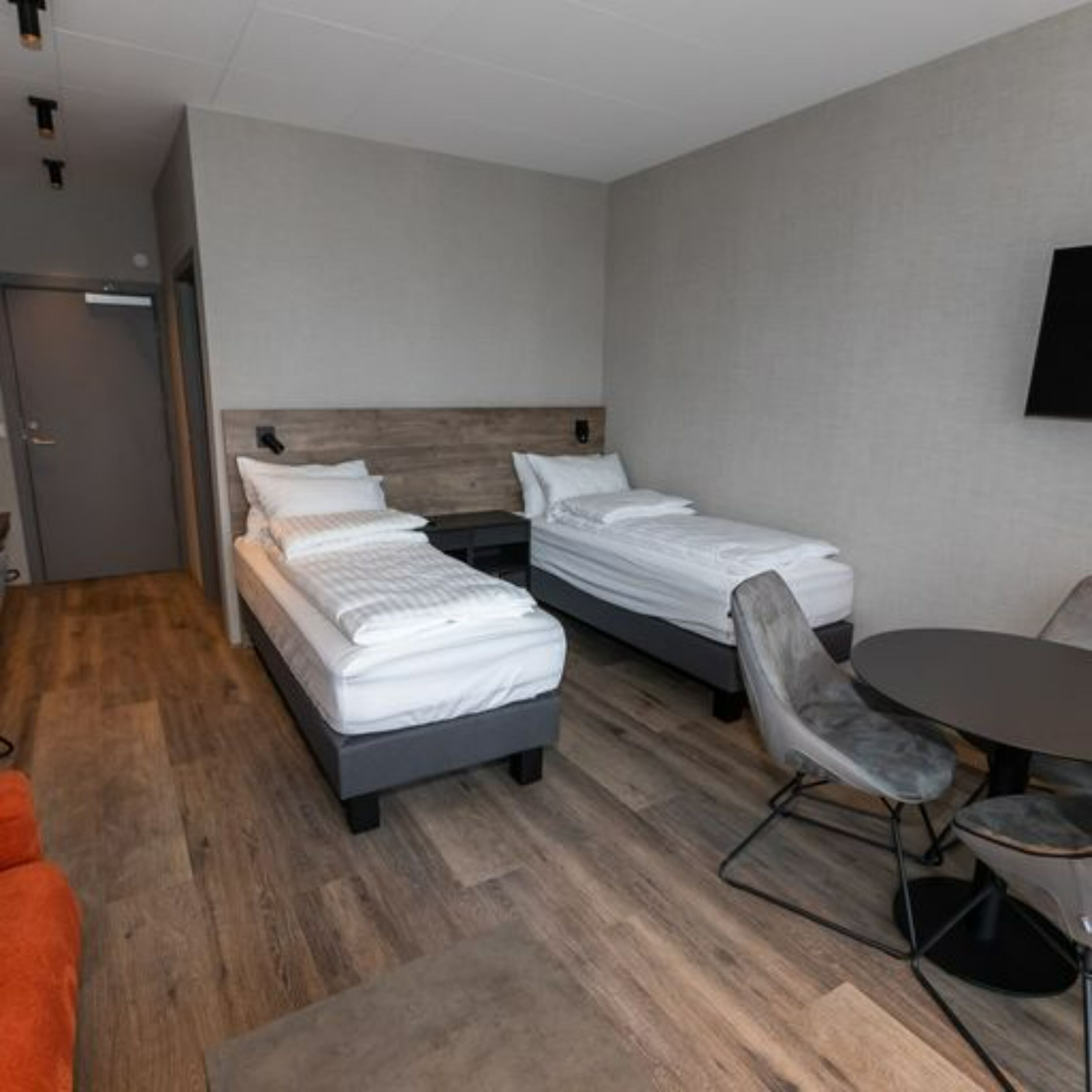 Una habitación de hotel con dos camas individuales, una mesa redonda y una silla.