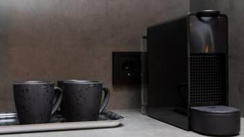 A modern kitchen with a coffee machine, two dark mugs, and a tray.