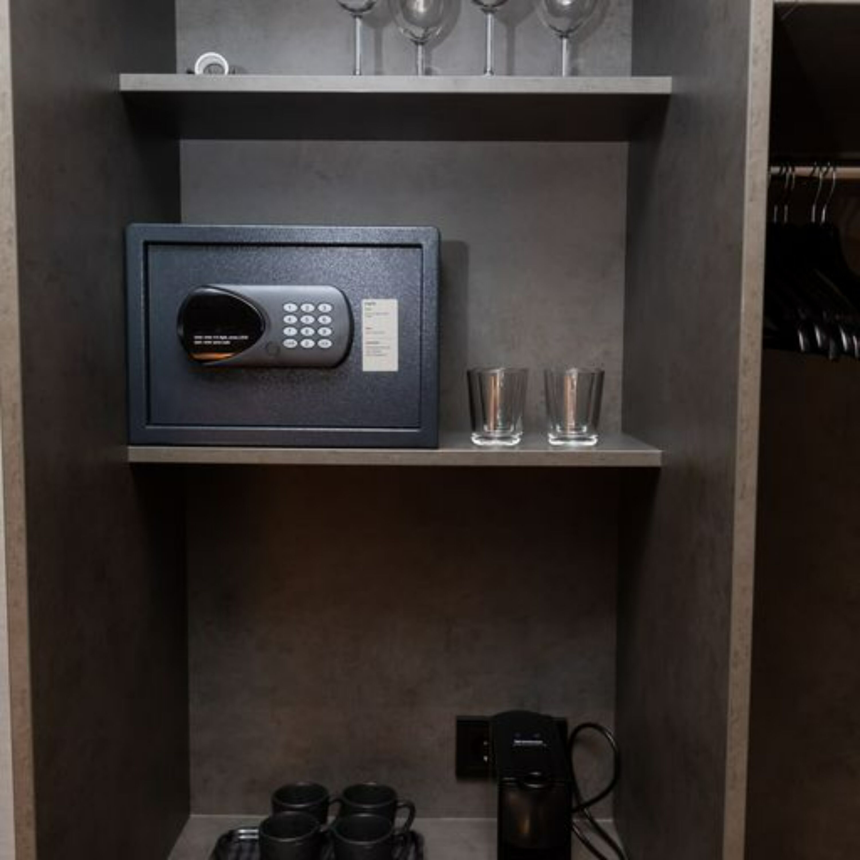 Un espace de rangement sécurisé doté d’un système de verrouillage à clavier, d’une machine à café et de deux verres posés sur une étagère.