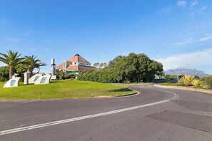 A curved road with a house and greenery in the background.