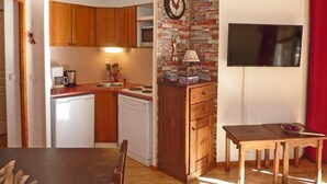 A compact kitchen with wooden cabinets, a built-in microwave, and a red curtain. - Resort center, 1st floor, swimming pool, sauna, balcony, tv, ski locker, 50m², Les Orres (Les Orres)