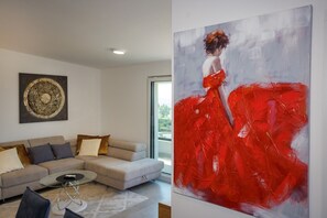 A modern living room with a beige sofa, a coffee table, and a large abstract painting.