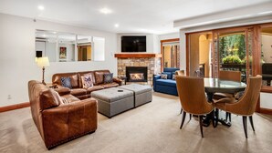 A living room with a brown leather sofa, a glass-top coffee table, and a fireplace. - Lionsquare Lodge North #294 1 Bedroom Condo by RedAwning (Vail)