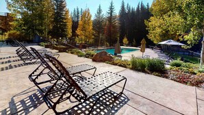 A poolside area with lounge chairs, a pool, and surrounding trees. - Lionsquare Lodge North #294 1 Bedroom Condo by RedAwning (Vail)