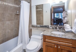 Un baño con bañera, inodoro y tocador con lavabo.