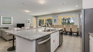 A modern kitchen with granite countertops, stainless steel appliances, and a large island with a sink. - Beautiful 9 bedroom pool home located in the Solterra Resort! 9 Home by RedAwning (Davenport)