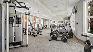 A gym with various exercise machines, a large mirror, and a window with a view of greenery. - Beautiful 9 bedroom pool home located in the Solterra Resort! 9 Home by RedAwning (Davenport)