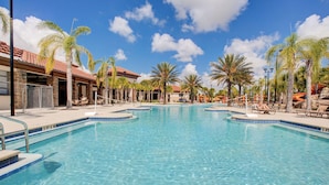 A large outdoor swimming pool with clear blue water, surrounded by palm trees and lounge chairs. - Beautiful 9 bedroom pool home located in the Solterra Resort! 9 Home by RedAwning (Davenport)