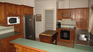 Une cuisine avec des meubles de rangement en bois, un four à micro-ondes, un réfrigérateur, un évier et une cuisinière.