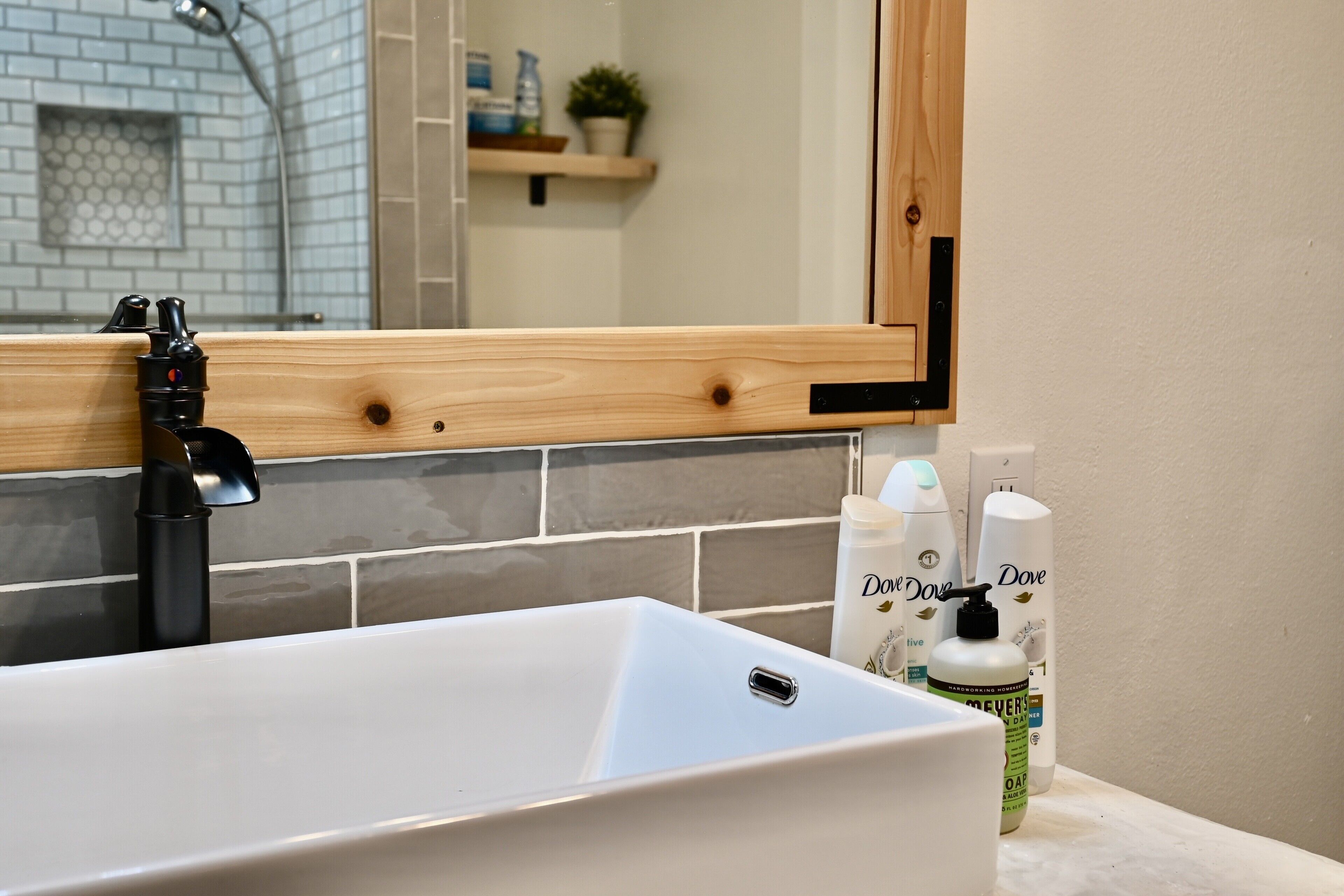 A bathroom with a white sink, a mirror with a wooden frame, and two Dove deodorant bottles on the counter.
