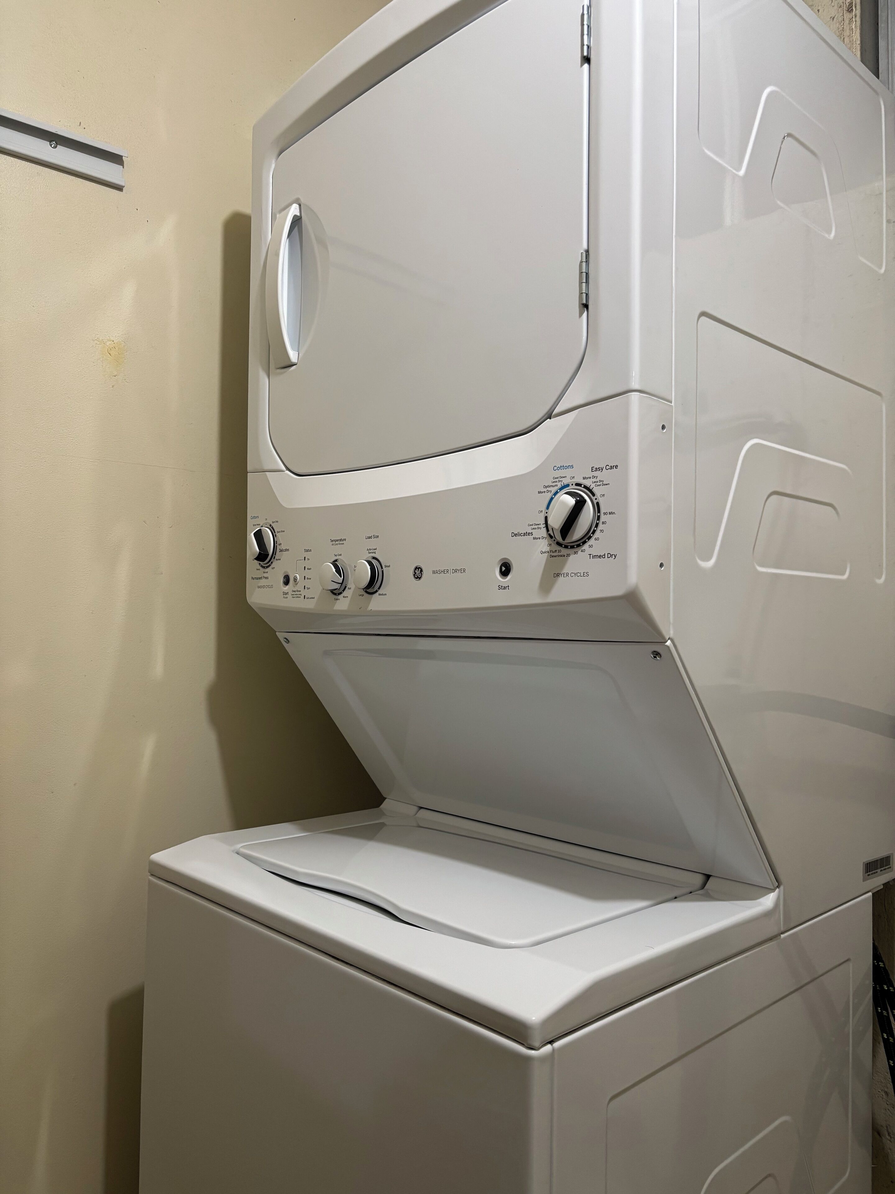 Een voorlader wasmachine-droger combinatie met bedieningsknoppen en labels voor verschillende instellingen.