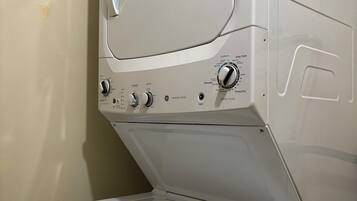 Een voorlader wasmachine-droger combinatie met bedieningsknoppen en labels voor verschillende instellingen.