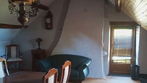 Et værelse med et træspisebord, to stole, en sofa og en hængende lampe.