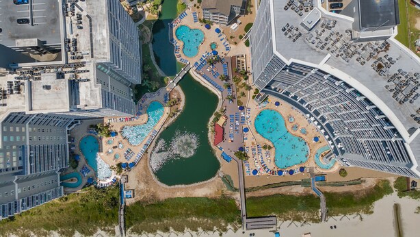 Vue aérienne d’un complexe hôtelier doté de plusieurs piscines, d’un port de plaisance et d’un parking.