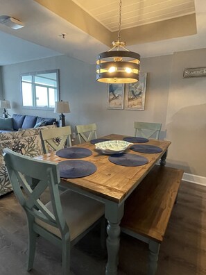 Un coin repas avec une table en bois, des chaises bleues et un luminaire suspendu.