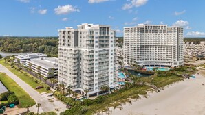 Un hôtel de grande hauteur doté de nombreux balcons, d’un espace piscine et offrant une vue sur la plage.