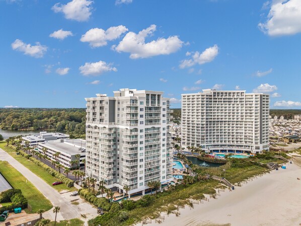 Un hôtel de grande hauteur doté de nombreux balcons, d’un espace piscine et offrant une vue sur la plage.