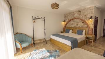 Un dormitorio con una cama grande, cabecera de madera, pared de piedra, una silla colgante y una lámpara de pie.