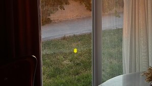 A room with a large window, curtains, and a view of a sunset with hot air balloons. - Soleado Capadocia Hotel (Nevsehir)