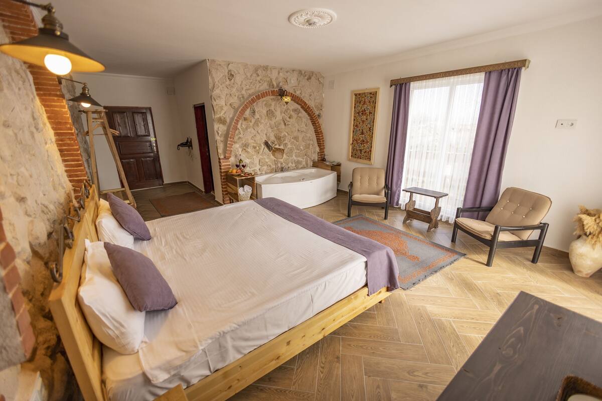 Ein Schlafzimmer mit einem hölzernen Bett, einer Steinwand, einer Badewanne und einem Sessel.