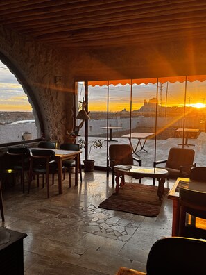 A room with a large window overlooking a landscape, furnished with chairs and a table. - Soleado Capadocia Hotel (Nevsehir)