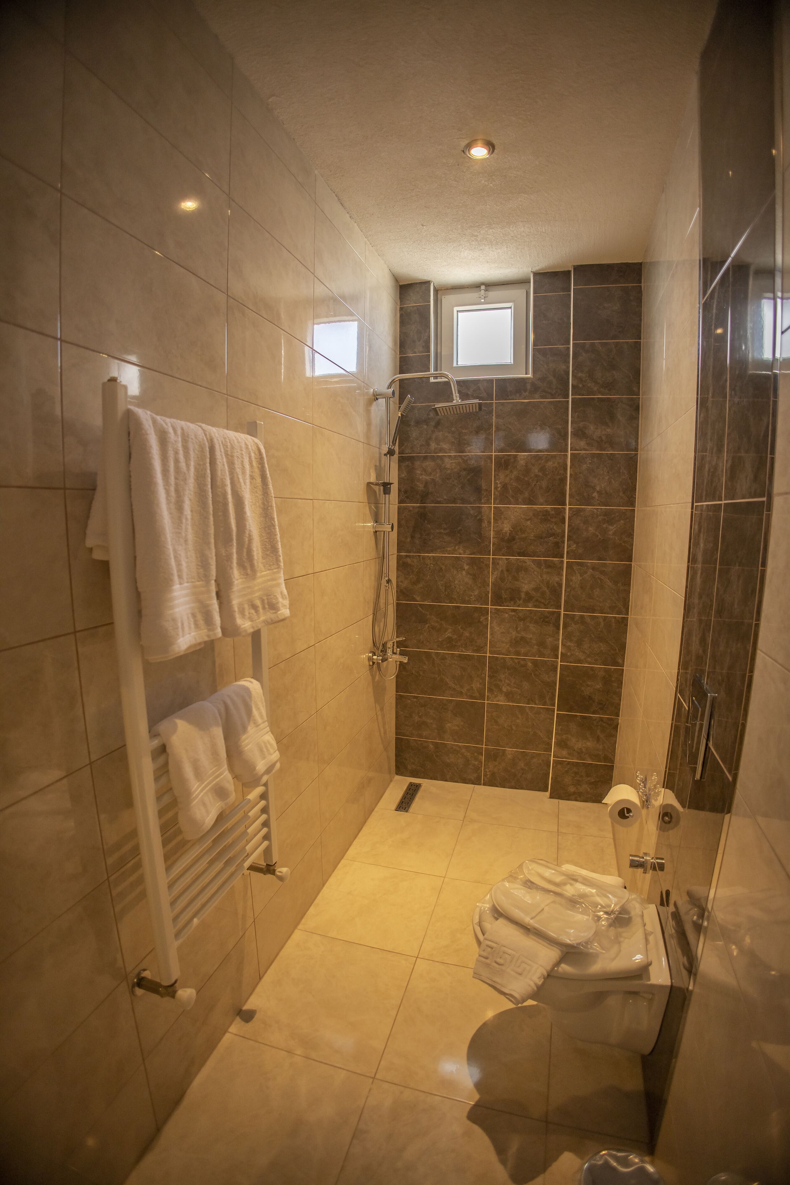 Un baño moderno con ducha, inodoro y un perchero con varias toallas.