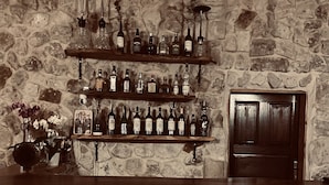 A bar area with wooden shelves displaying bottles, a stone wall, and a wooden door. - Soleado Capadocia Hotel (Nevsehir)