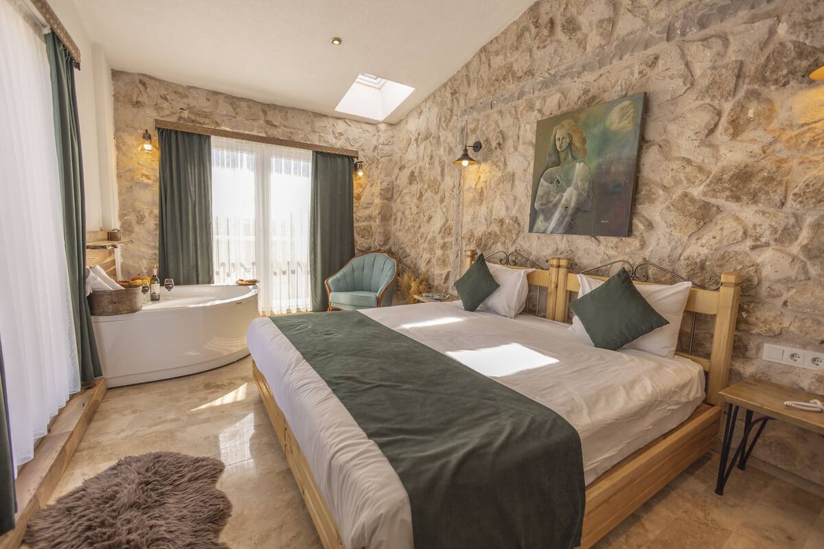 Ein Schlafzimmer mit einem großen Bett, einer Badewanne und einer Steinwand.