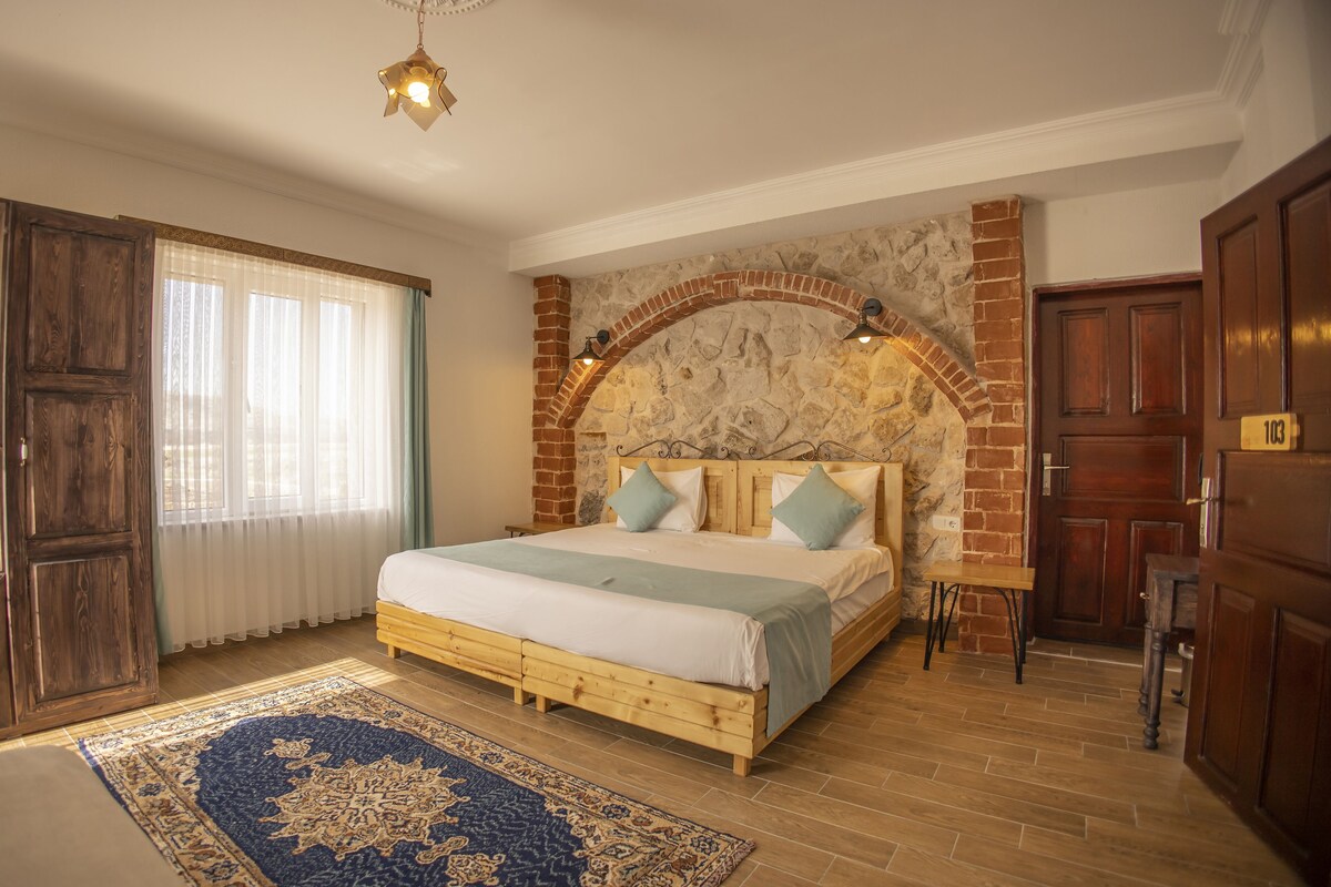 A bedroom with a stone fireplace, wooden bed, and a large rug.