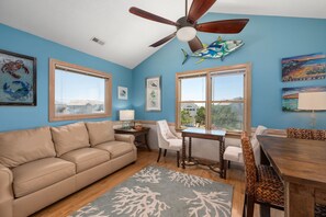 A room with a ceiling fan, a dining table with chairs, a sofa, and large windows with a view. - Good Day Sunshine-Oceanside, pool, hot tub, dog friendly, close to the beach! (Nags Head)