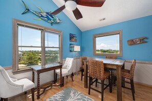 A dining area with a view, a ceiling fan, and a fish decoration. - Good Day Sunshine-Oceanside, pool, hot tub, dog friendly, close to the beach! (Nags Head)