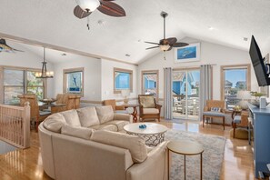 A spacious living room with a large L-shaped sectional sofa, a round coffee table, and a ceiling fan.