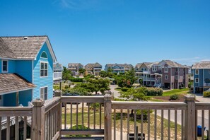 A residential area with multiple two-story houses, a wooden deck, and a clear blue sky.