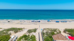 Ein Strand mit klarem, blauem Wasser, sandigem Ufer und Strandsonnenschirmen.
