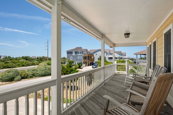 A wooden deck with white railings, overlooking a residential area with houses and a road. - Good Day Sunshine-Oceanside, pool, hot tub, dog friendly, close to the beach! (Nags Head)