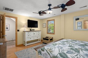 A bedroom with a bed, a ceiling fan, a dresser, a television, and a window with blinds. - Good Day Sunshine-Oceanside, pool, hot tub, dog friendly, close to the beach! (Nags Head)