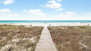 A wooden boardwalk leading to a beach with clear skies and distant people. - Gulf front retreat with pool, hot tub, & beach service—perfect for family groups (Panama City Beach)