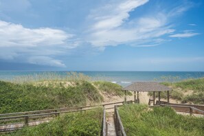 A wooden boardwalk leading to a beach with a gazebo.