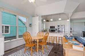 A modern kitchen with white cabinets, a central island, and wooden chairs.