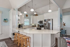 A kitchen with a central island, bar stools, a microwave, and a refrigerator.