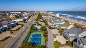 Un quartier résidentiel situé sur la côte, avec des maisons, un court de tennis et une plage.