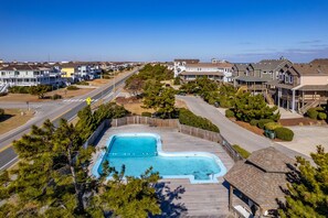 A residential area with a swimming pool surrounded by houses and a road.