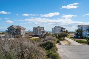 A coastal residential area with modern houses, a clear sky, and a beach in the background.