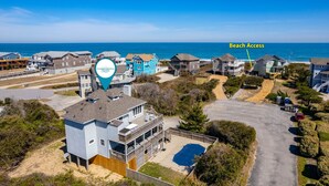 A coastal community with beach access, featuring a mix of residential buildings and a large swimming pool. - Tidy Duck-Semi-oceanfront with views, private pool, hot tub, steps to the beach! (Duck)