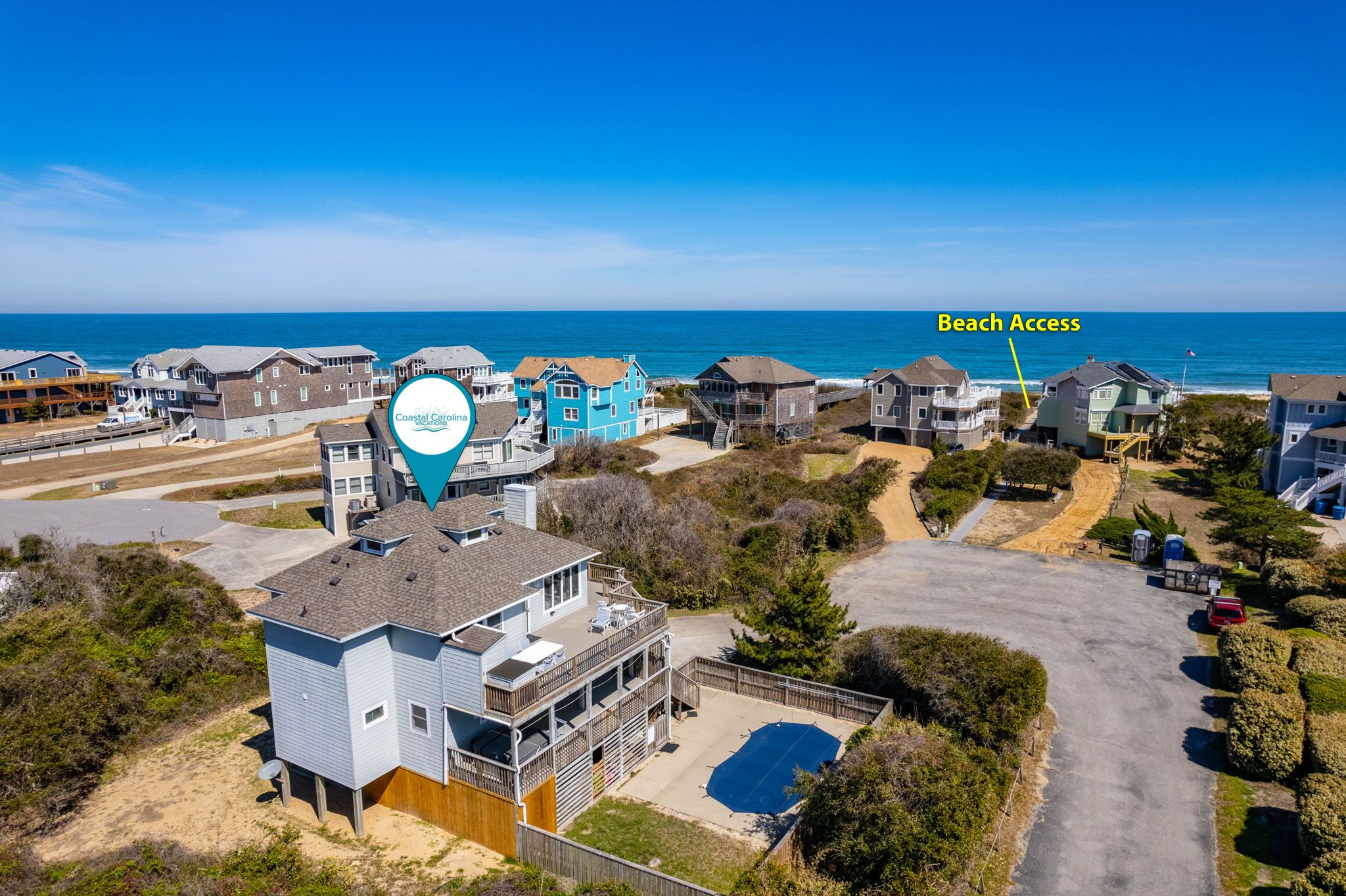 Una comunidad costera con acceso a la playa, que cuenta con edificios residenciales y una gran piscina.