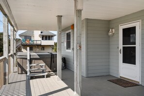A covered porch with a hot tub, a wooden deck, and a door with a doormat. - Tidy Duck-Semi-oceanfront with views, private pool, hot tub, steps to the beach! (Duck)