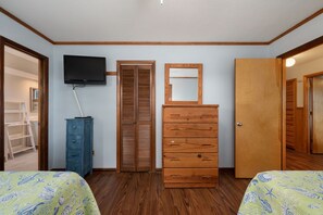 A bedroom with two beds, a dresser, a television, and a wardrobe. - Tidy Duck-Semi-oceanfront with views, private pool, hot tub, steps to the beach! (Duck)