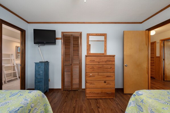 Een slaapkamer met twee bedden, een dressoir, een televisie en een kledingkast.